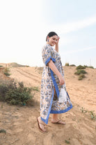 Woman in a floral dress with blue trim standing in a desert landscape - Love Protect Sustain