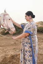 Woman in a patterned dress standing next to a horse in an outdoor - Love Protect Sustain