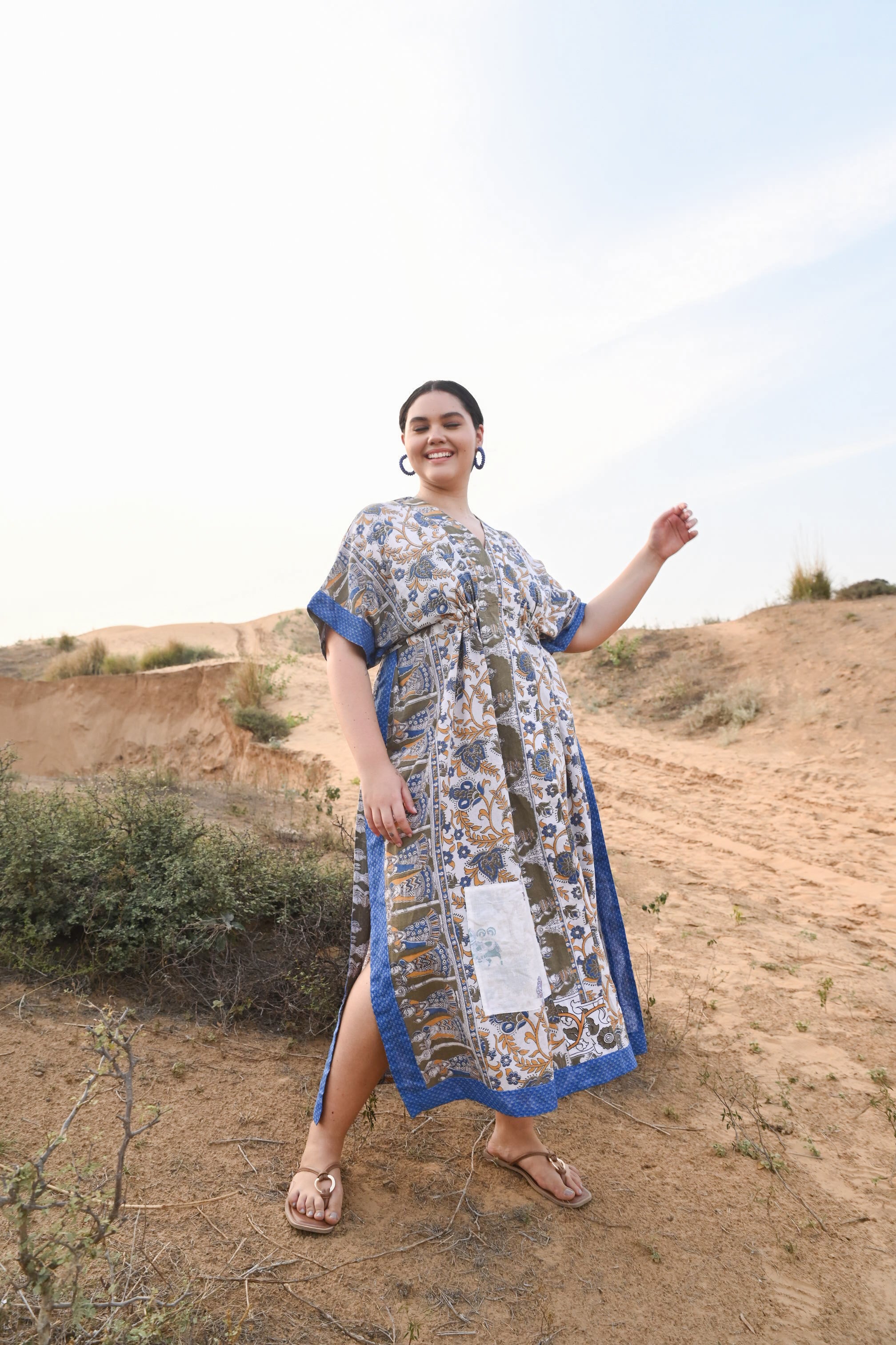 Woman in a patterned dress standing on a desert landscape  - Love Protect Sustain